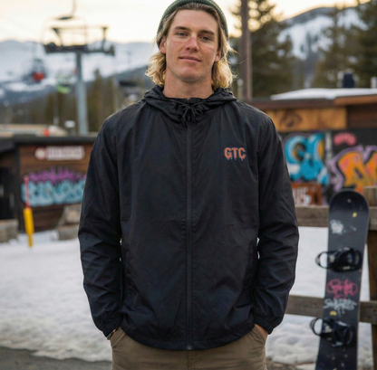 Person wearing a black jacket with 'GTC' logo in a snowy outdoor setting